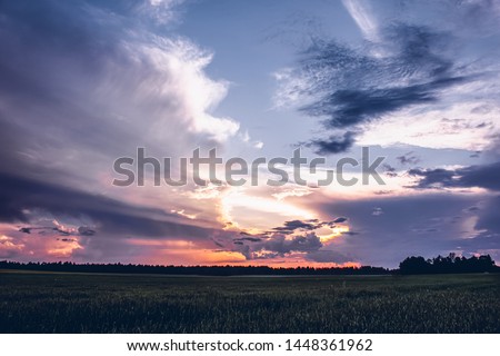 Sunset with dramatic purple clouds over a field in rural Estonia