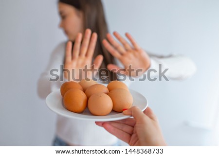 Woman refusing to eat eggs. Egg Free Affected Allergy Banned Restriction. Young beautiful woman holding fresh egg at home with open hand doing stop sign with serious and confident expression