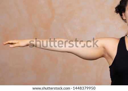 A close up view on the stretched out arm of a Caucasian lady. Saggy muscle and fat is seen in the upper arm area. Commonly called bingo wings and corrected with plastic surgery. Royalty-Free Stock Photo #1448379950