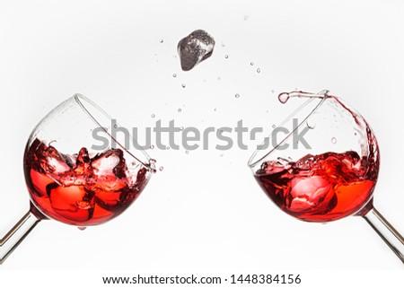 Two glasses of red liquid and icecubes with splash on white background
