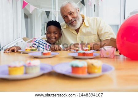 Front view of African-American boy birthday. He taking a picture with his grandfather. Authentic Senior Retired Life Concept