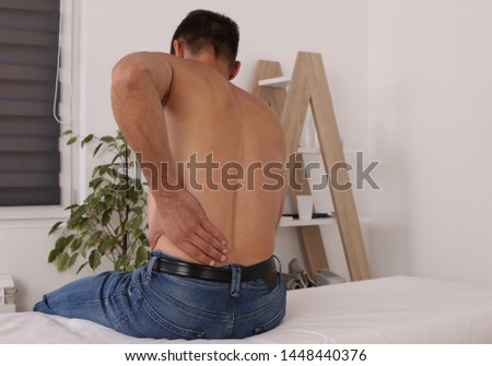 Man suffering from back pain during medical exam. Chiropractic, Osteopathy, Physiotherapy. Alternative medicine, pain relief concept.