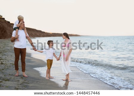 Family of four walking along the seashore. Parents and two sons. Happy friendly family