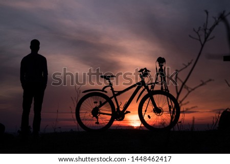Photography and cycling hobbies. Amazing sunset, shadow (silhouette) of tripod, bicycle and human