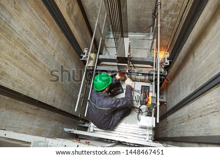 lift machinist repairing elevator in lift shaft Royalty-Free Stock Photo #1448467451