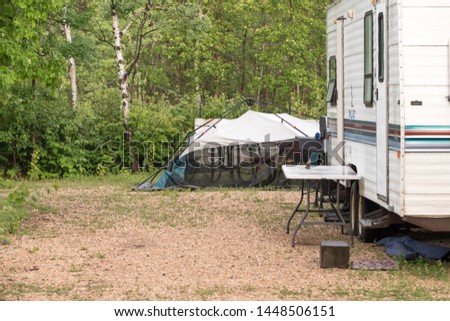 a camping site pictures in deep woods with modern camping equipment like tents, RV, picnic benches