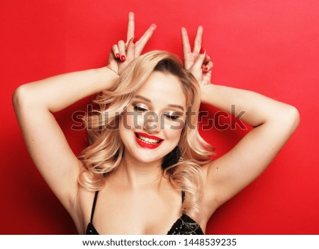 Gorgeous blonde woman in an evening dress flirty and playful on a red background