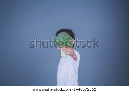 Children holding vegetables on a gray background.