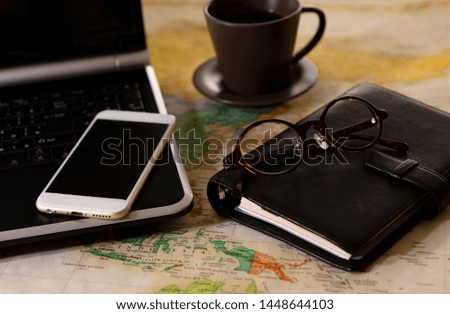 Laptop, notebook and glasses on the map
