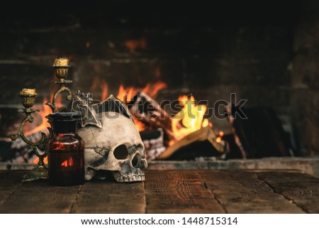 Alchemist or wizard or witch doctor table with magic accessories above on a burning fire background. Royalty-Free Stock Photo #1448715314