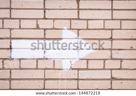 An arrow painted on an old brick wall