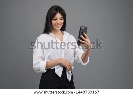 beautiful woman looking at her phone isolated over grey