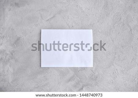 Blank sheet of white paper for design banner or card on grunge gray background, selective focus. Clear page with empty space for image or text on rough grey backdrop. Mockup concept 