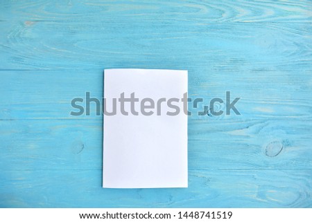 Blank sheet of white paper for design banner or card on textured blue background, selective focus. Clear page with empty space for image or text on wooden turquoise backdrop. Mockup concept 