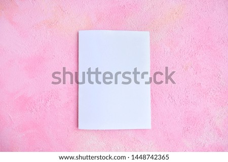 Blank sheet of white paper for design banner or card on textured pink background, selective focus. Clear page with empty space for image or text on pink plaster backdrop. Mockup concept 