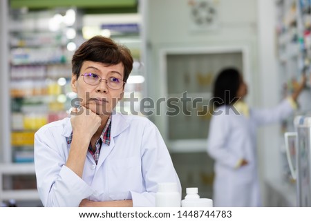 an elderly asian women pharmacist she had problems with depression while working in pharmacy store in Thailand Royalty-Free Stock Photo #1448744783