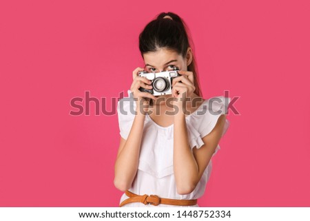 Young girl with photo camera on color background