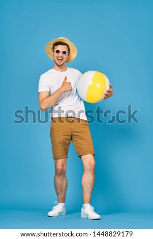 A man in shorts and a t-shirt a hat on his head, an inflatable ball and sneakers is a fun vacation game