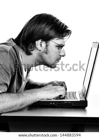 Concentrated young man working on his laptop on white background. Monochrome portrait