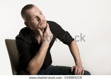 young man sitting looking up, white background, thinks, optional