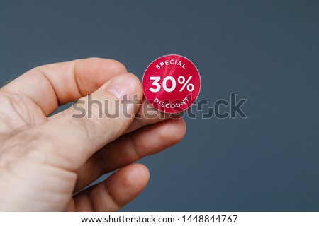 Man hand with glue sticked discount sale 30 percent special price red tags to be glued on goods during sale season - isolated gray background