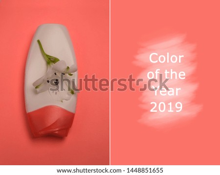 Beauty background in fashionable coral color of the year 2019. White cosmetic bottle with white flower on top. Trendy photo. Copy space. Renovation concept. Color trends of the year.Creative image.