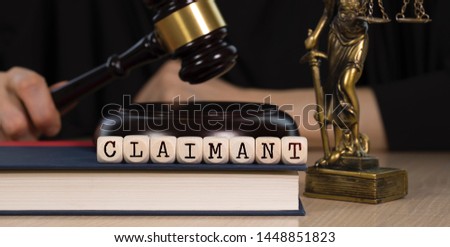 Word  CLAIMANT composed of wooden dices.  Wooden gavel and statue of Themis in the background. Closeup Royalty-Free Stock Photo #1448851823