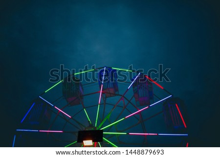 view of colourful neon rolling chair at night time at temple fair 