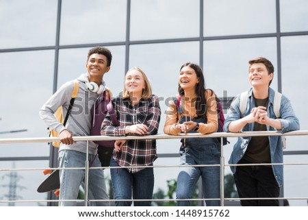 cheerful and happy teenagers smiling and looking away outside 