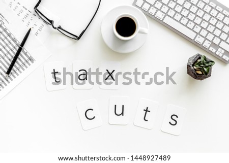 work desk with tax cuts text, keyboard, coffee and accounting calculation on white background top view