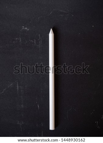 White pencil chalk lying on chalk board background
