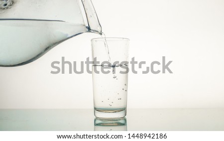 Motion with water, filling water in clear glass isolated on white textured background