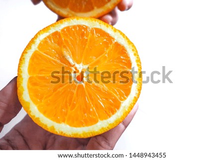 Fresh orange cut in half on the hand on a white background.