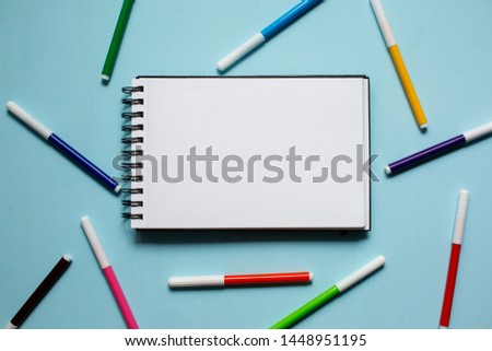 Notepad and markers on blue wooden background top view