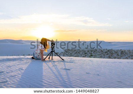 Woman photographer with tripod doing time lapse in white sands dunes national monument in New Mexico view of sunset