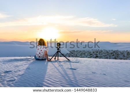 Woman girl photographer with tripod doing time lapse with camera in white sands dunes national monument in New Mexico view of sunset