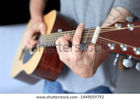 close up acoustic guitar in musician hands, small depth of field