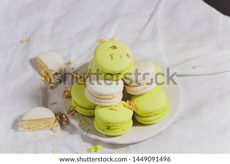 Many colorful macaroons on white ceramics plate over the table.