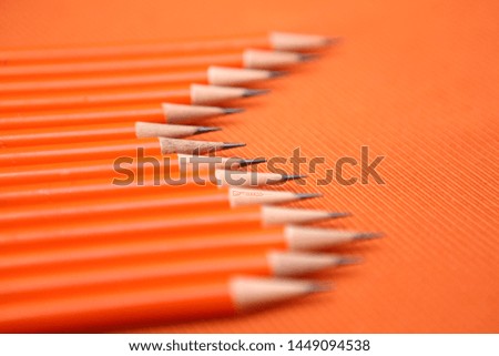orange pencil in queue on orange background