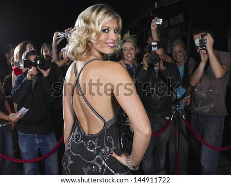 Portrait of attractive female celebrity posing in front of fans and paparazzi