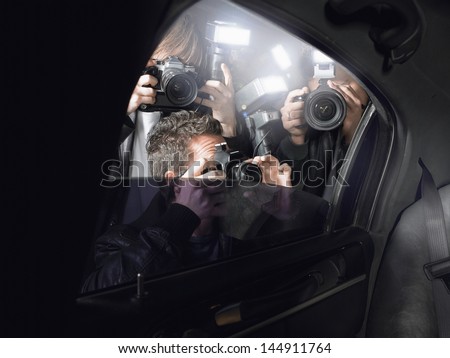 Paparazzi taking pictures through car window Royalty-Free Stock Photo #144911764
