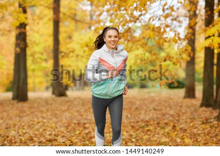 fitness, sport, people and healthy lifestyle concept - young woman running in autumn park