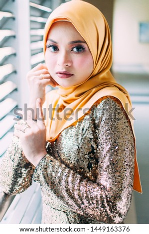 Beautiful female model wearing bright color "baju kurung" dress with hijab, a modern lifestyle outfit for Muslim woman isolated over white background. Eidul fitri fashion and beauty concept. 