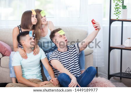 Young people making selfie indoors. Group of friends making a shot on the smartphone. People taking a pictire of themselves.