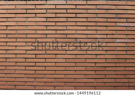 Close up outdoor view of part of a wall made of orange bricks. Pattern of rectangular elements with grey lines. Modern design with many parallel rectangles. Architectural picture. 