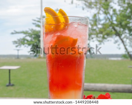 Glass of red coctail with ice, lemon, orange