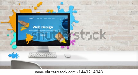 Web design studio concept with modern web site teme and web design text on computer display surrounded by color drops. Free space beside on brick wall for text.
