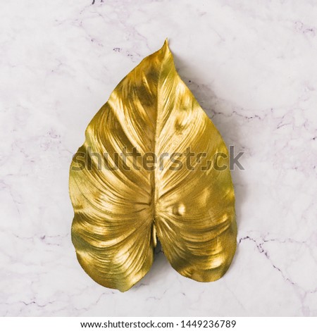 Creative layout made of golden tropical leaf on white marble texture background. Minimal summer exotic concept with copy space. Border arrangement background.