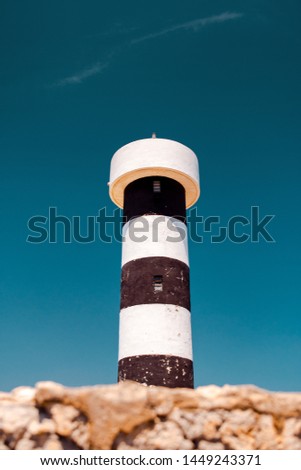 Black and white lighthouse at the coast on a sunny summer day with blue sky. Faro Colònia de Sant Jordi, Mallorca, Spain