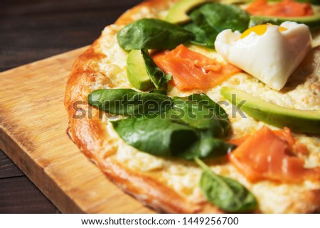 Pizza with avocado and salmon on wooden background